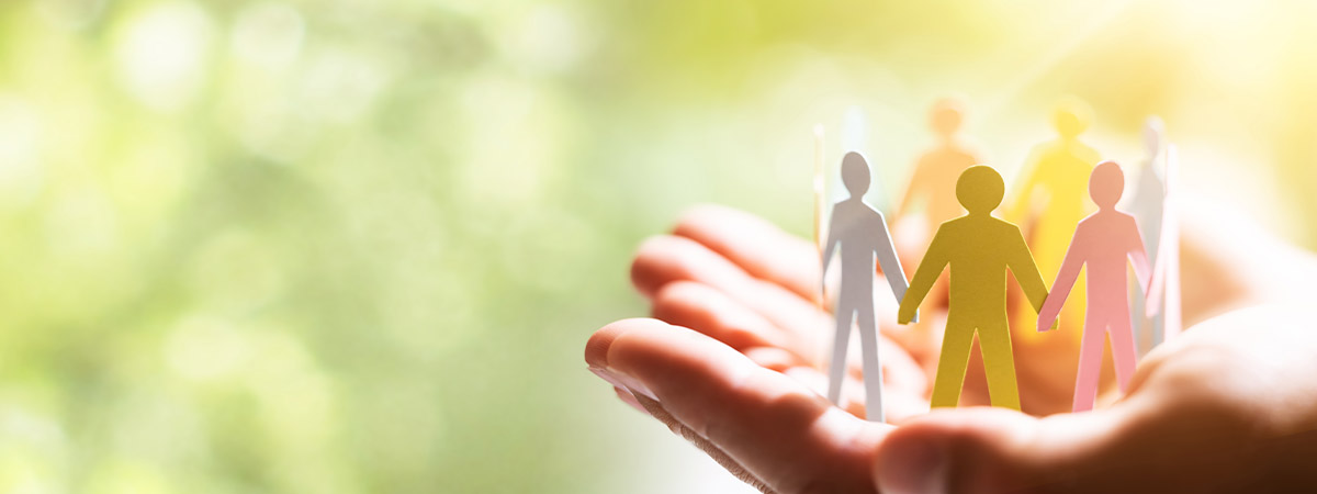 a pair of hands holding a circle of people with construction paper